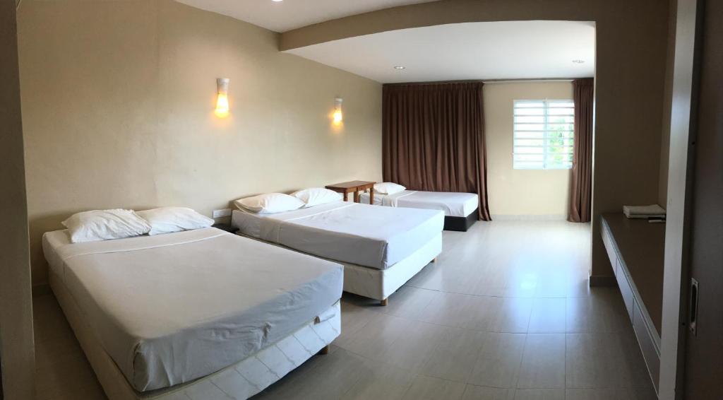 a hotel room with two beds and a table at Pantai GuestHouse in Kuantan