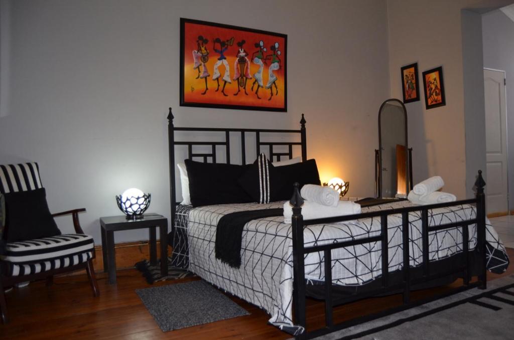 アリワル・ノースにあるSondela Bed & Breakfastのベッドルーム1室(ベッド1台、椅子、絵画付)