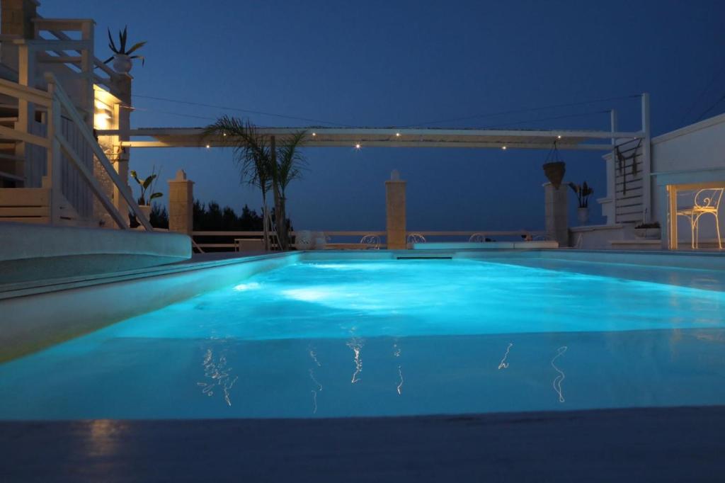 a large blue swimming pool at night at Playa del Mar - Adults Only in Monopoli