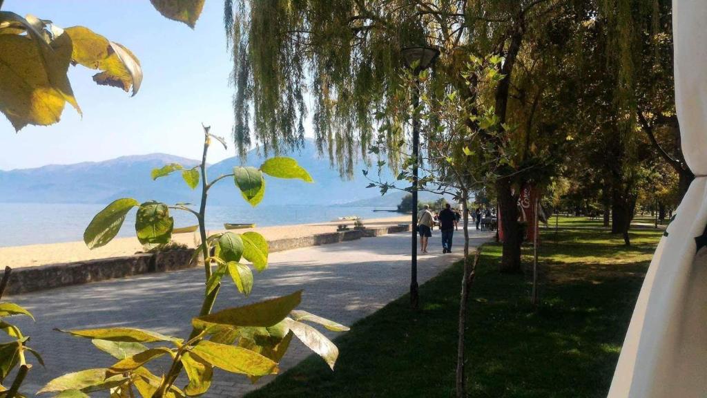 a person walking down a sidewalk next to a beach at Elio's Holiday Home in Pogradec