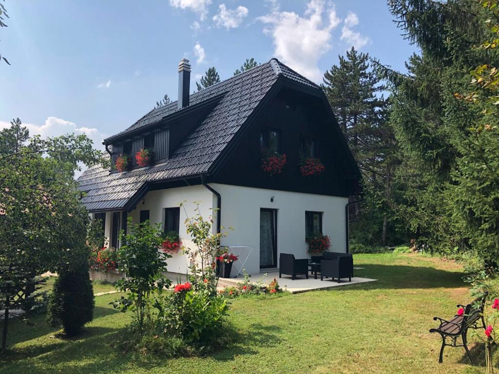 a small white house with a black roof at Plitvice Retreat Apartments in Rudanovac