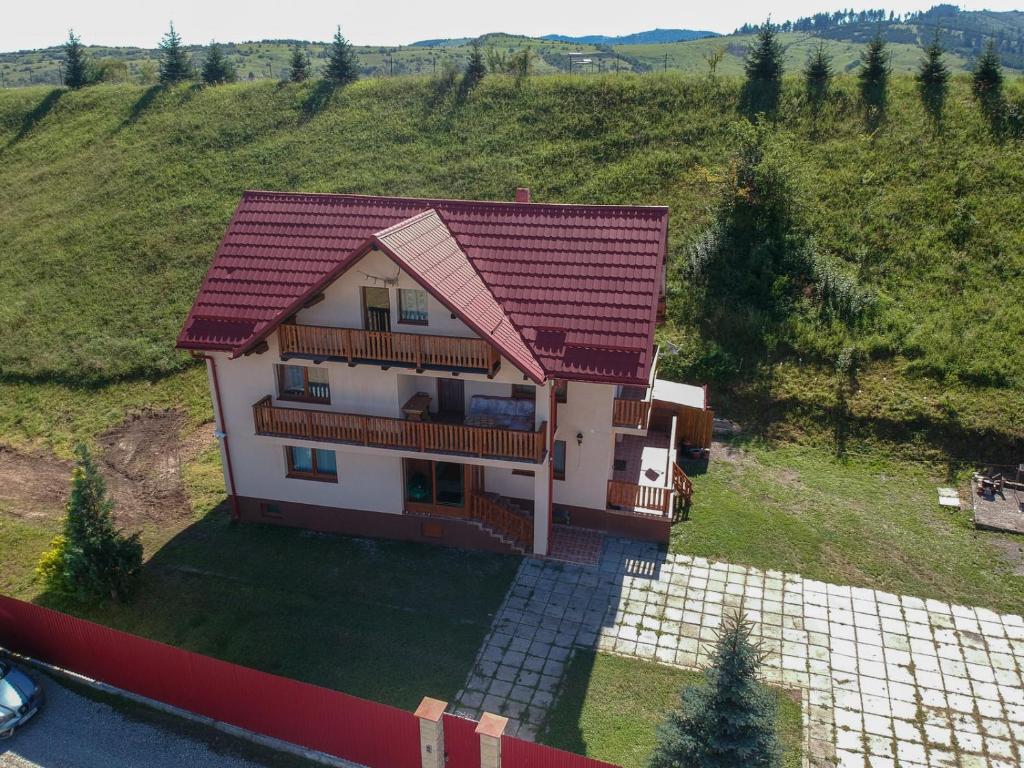 une maison avec un toit rouge sur une colline dans l'établissement Casa Din Gradina Lui Ioan, à Tărlungeni