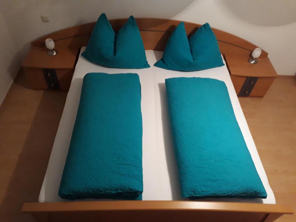 a bed with blue pillows on top of it at Gästehaus Klug in Sankt Stefan ob Stainz