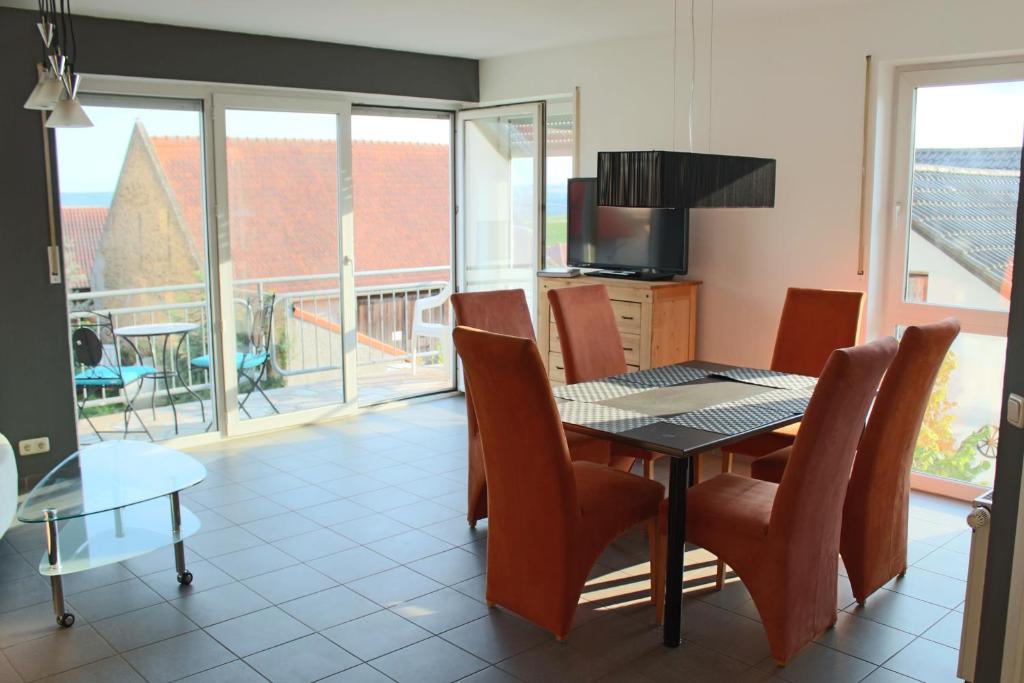 a dining room with a table and chairs and a balcony at Ferienwohnung Tropical in Vendersheim