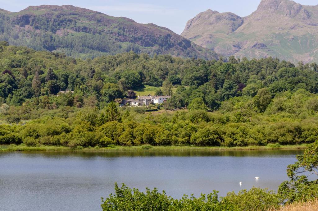 una casa en la orilla de un lago con montañas en el fondo en Eltermere Inn en Elterwater