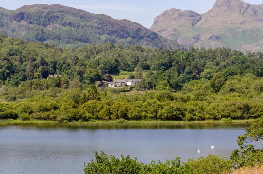a house on the shore of a lake with mountains in the background at Eltermere Inn in Elterwater