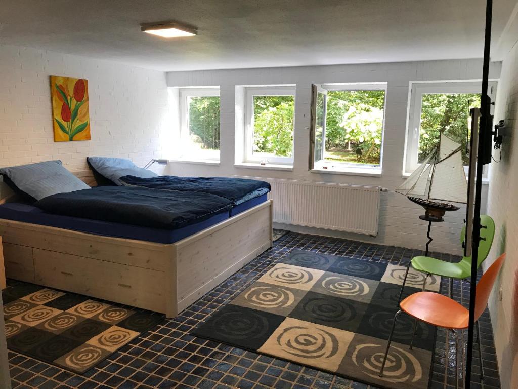 a bedroom with a bed and a chair and windows at Ferienhaus Atelier am Südhang in Worpswede