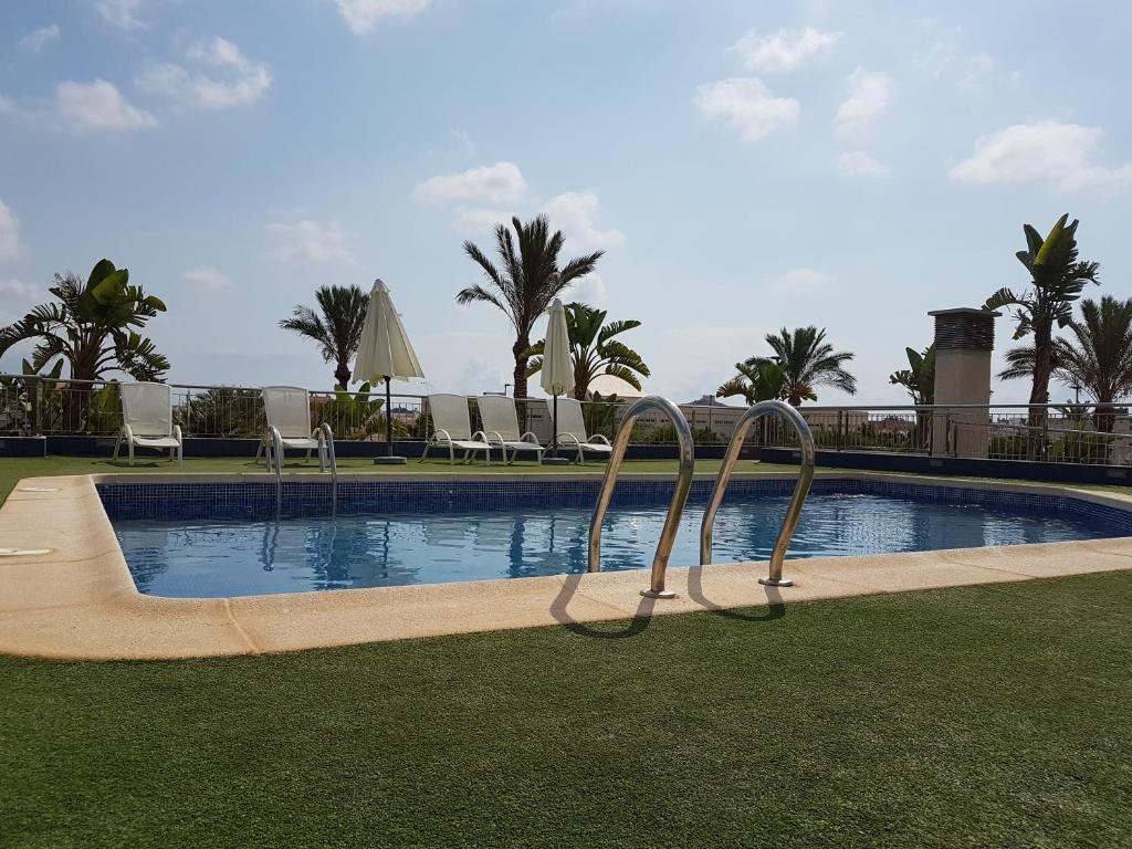 a swimming pool with chairs and trees and the ocean at La Loma in Águilas