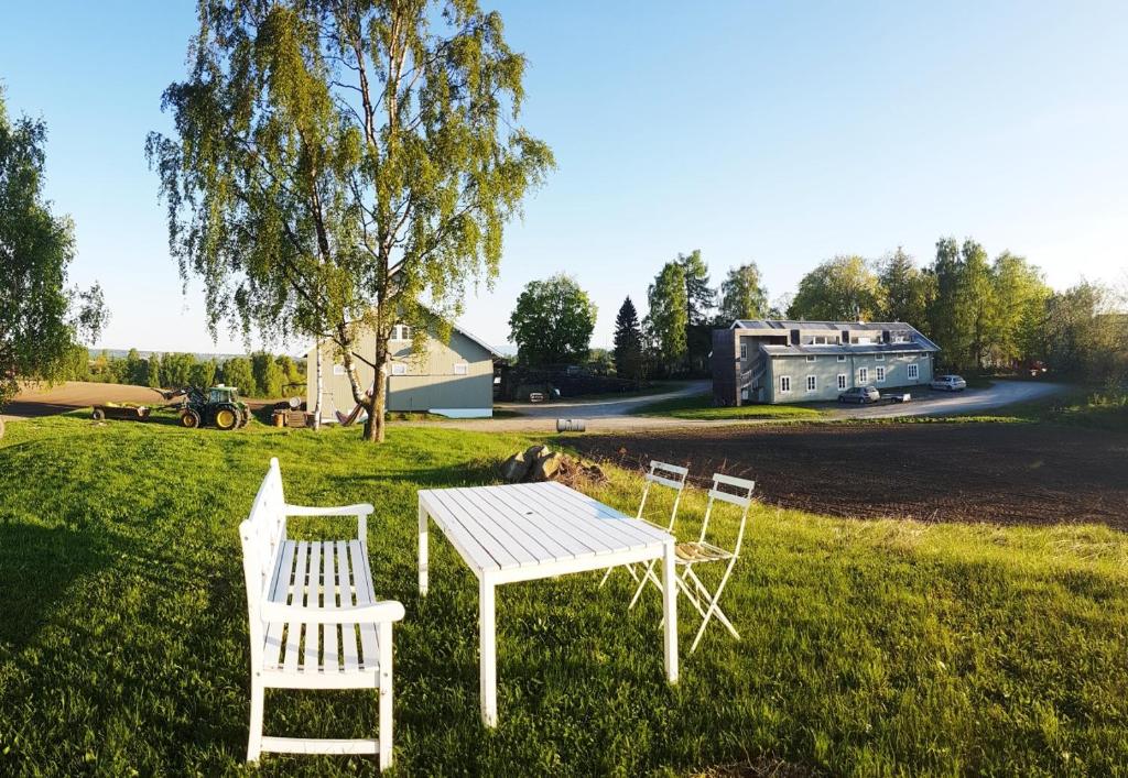 four white chairs and a table in the grass at Drengestua på Flagstad Østre in Hamar