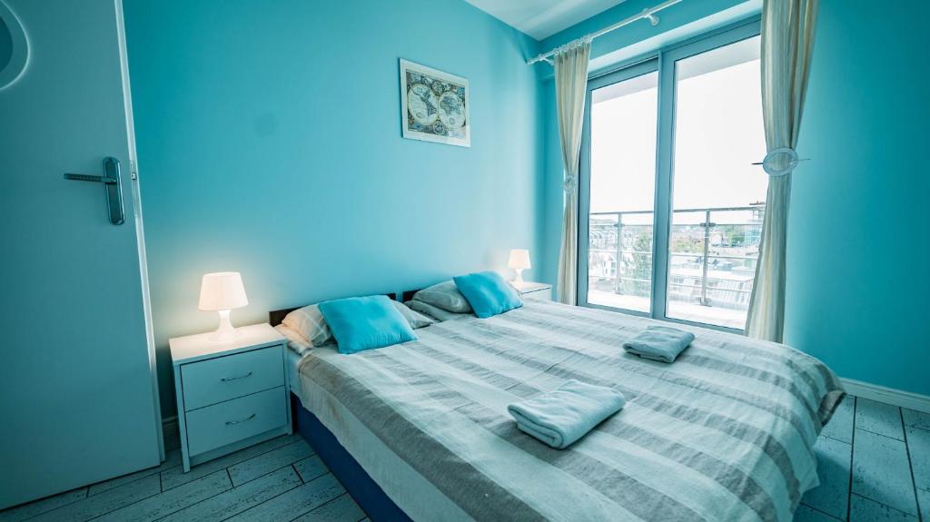ミエンジズドロイェにあるWechta E5の青い壁のベッド1台、窓が備わる青いベッドルーム1室が備わります。
