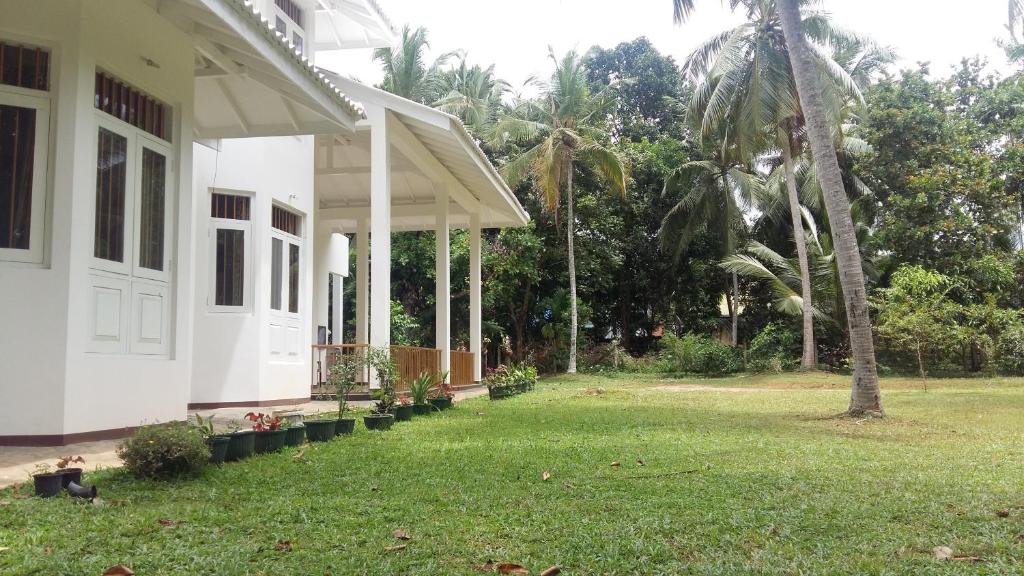 ein weißes Haus mit einem Hof mit einer Palme in der Unterkunft White House - Orange Hill Avenue in Ragama