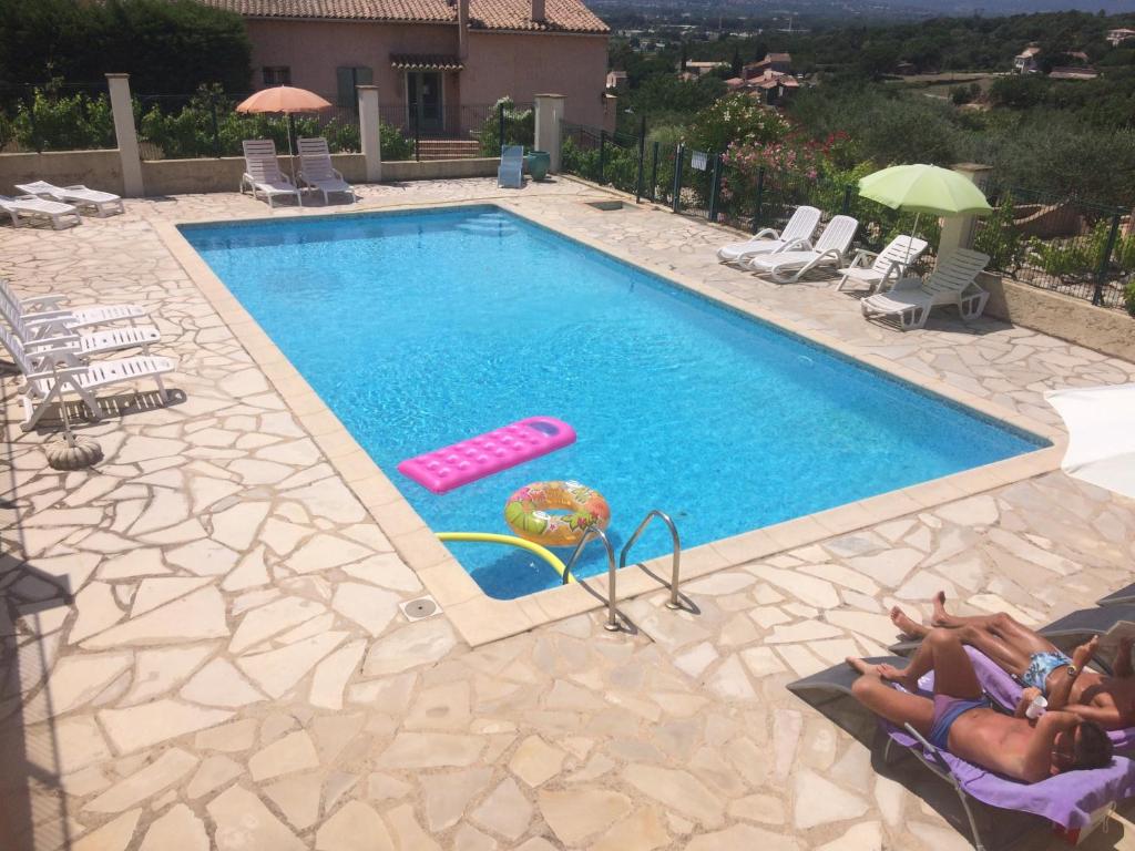 a swimming pool with two people laying in chairs next to it at Les Oliviers in Grimaud
