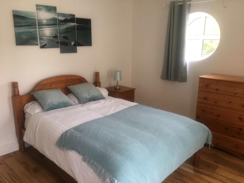 a bedroom with a bed with a blue blanket and a window at 5 Shell Hill Mews in Coleraine
