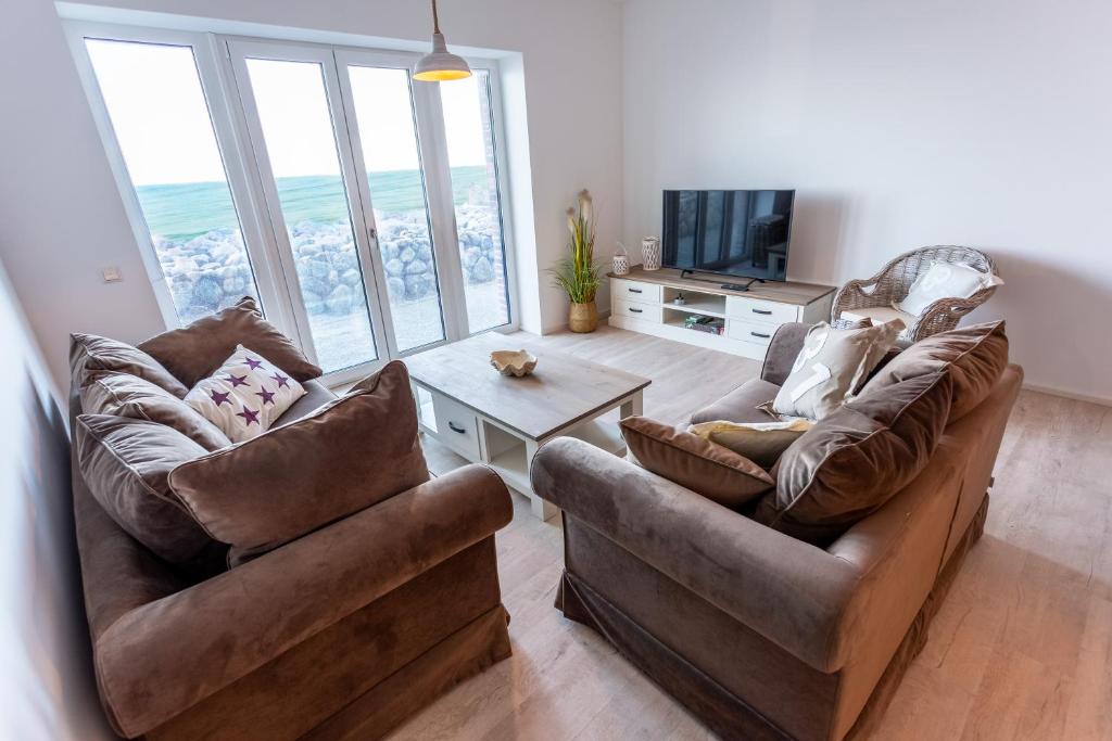 a living room with two couches and a tv at Komfort-Ferienwohnung Wellenbrecher by Meer-Ferienwohnungen in Olpenitz