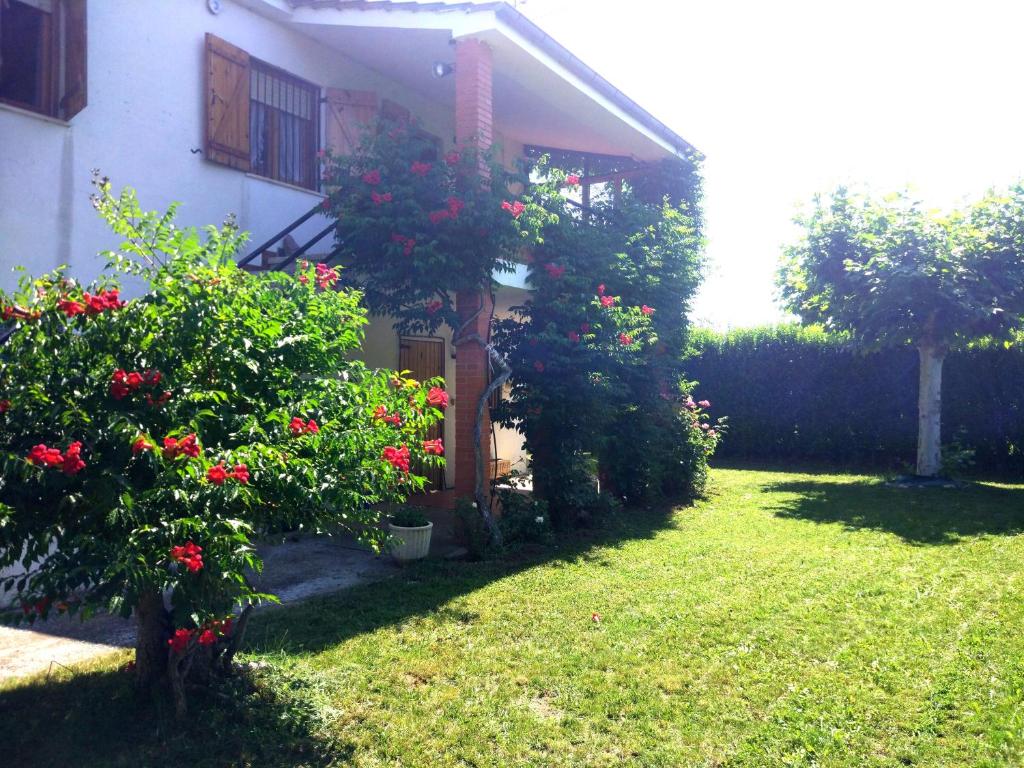 a house with red flowers in the yard at Chalet en el Orbigo in La Bañeza