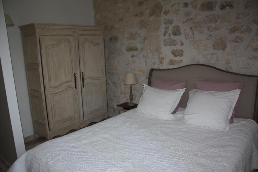 a bedroom with a bed with white sheets and a cabinet at Mas de Karlotte in Pernes-les-Fontaines