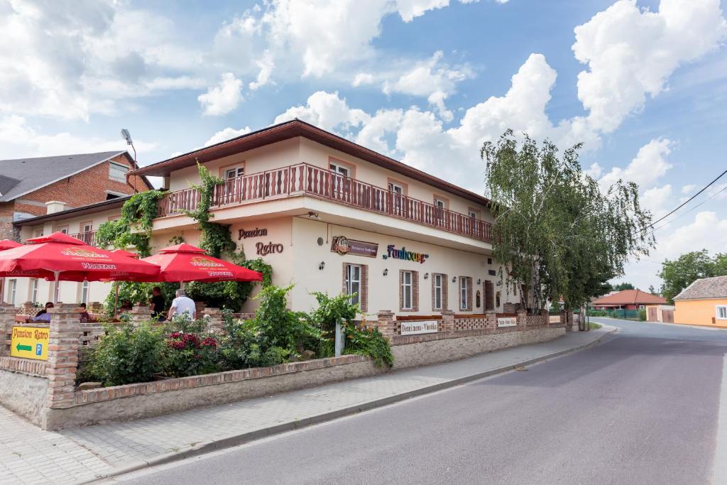 ein Gebäude mit roten Sonnenschirmen an der Straßenseite in der Unterkunft Retro Vrbovec in Vrbovec