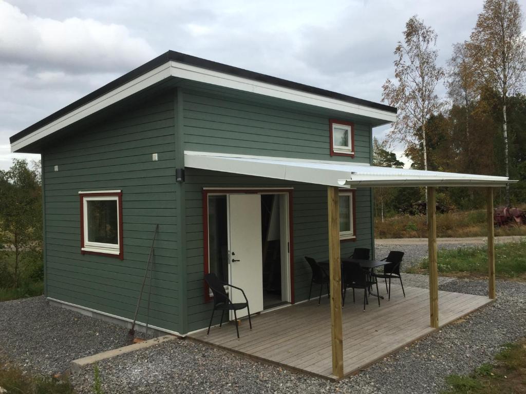 uma pequena casa verde com um deque de madeira em Larstorpsvägen 12 em Trollhättan