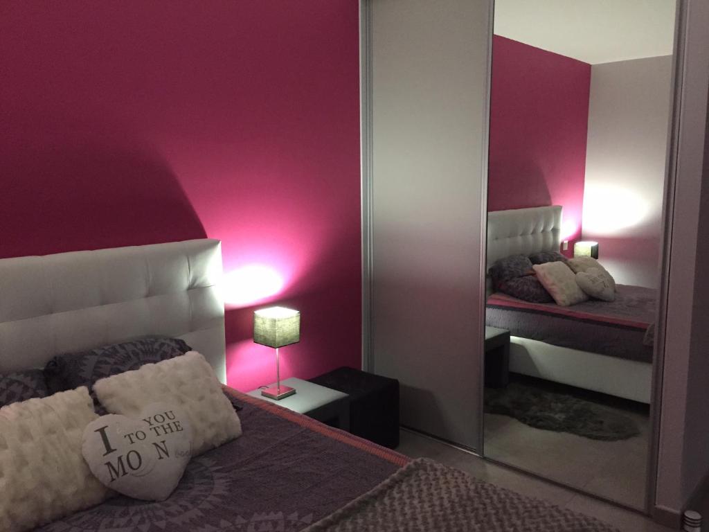 1 dormitorio con espejo y 1 cama con paredes moradas en La chambre rose, en Mâcon