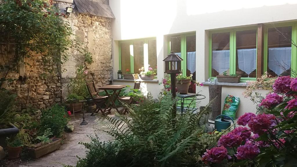 a garden with a table and chairs and flowers at La maisonnette in Les Andelys