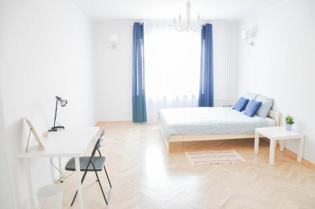 a white bedroom with a bed and a desk at HaLo Rooms City Centre in Warsaw