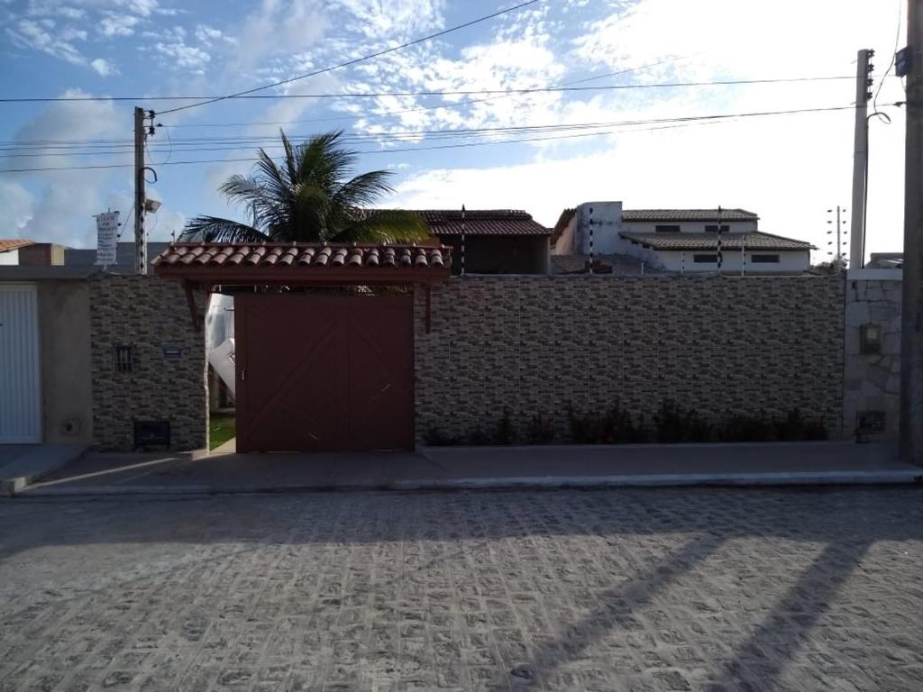 a brick wall with a garage with a palm tree behind it at Casa na Barra de São Miguel Barra Mar in Barra de São Miguel