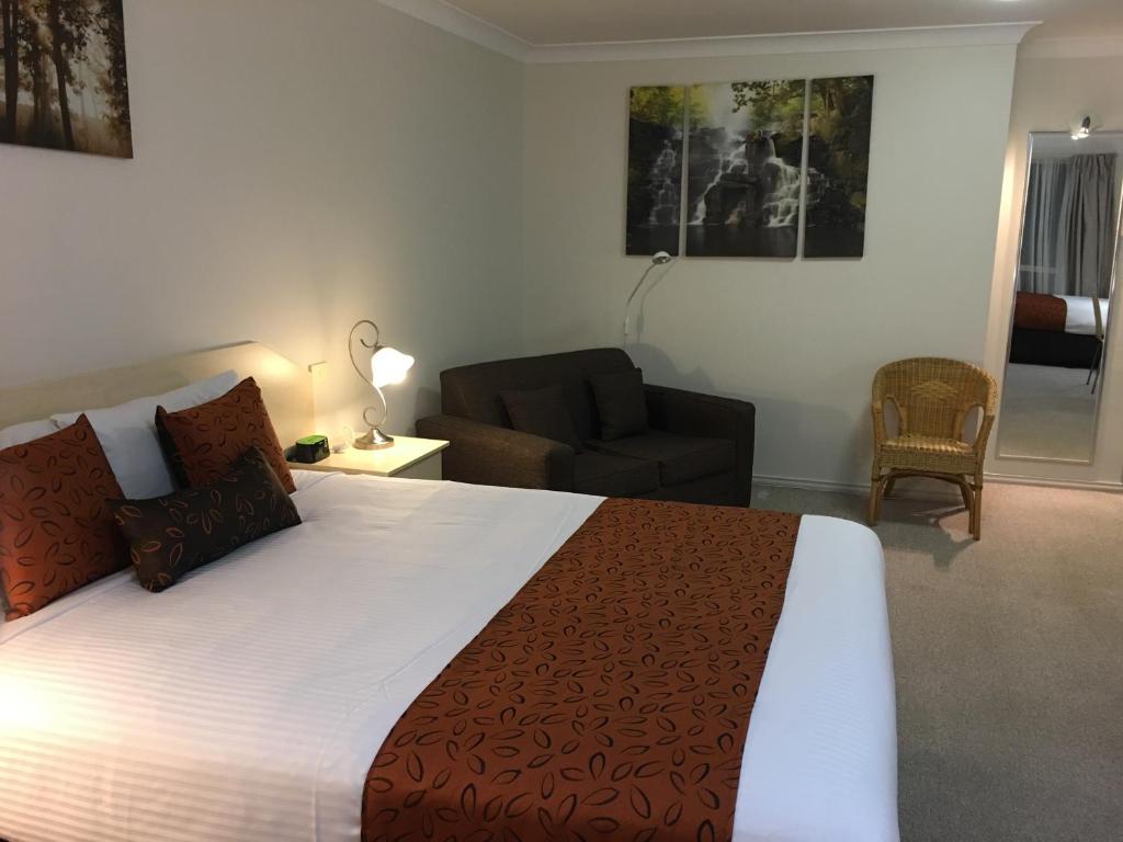 ein Schlafzimmer mit einem Bett, einer Couch und einem Sessel in der Unterkunft Tuckerbox Motor Inn in Gundagai