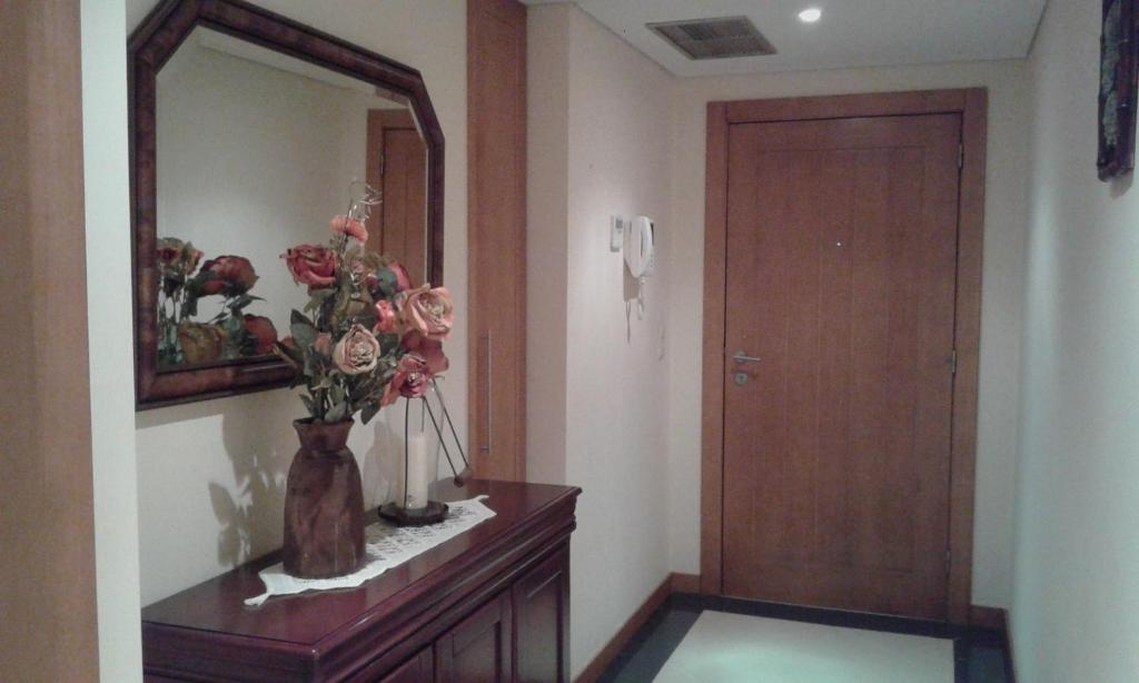 ein Zimmer mit einem Spiegel und einer Vase mit Blumen auf der Kommode in der Unterkunft Casa Arrudas in Ponta Delgada