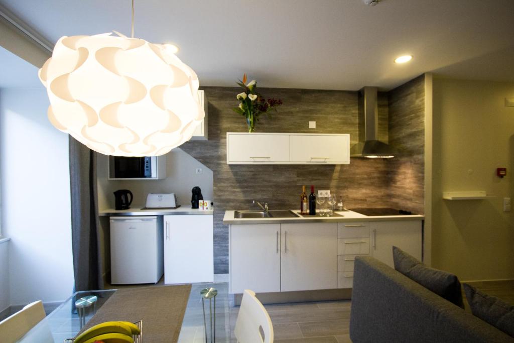 cocina y sala de estar con mesa y lámpara de araña en MS Apartamentos, Setúbal en Setúbal