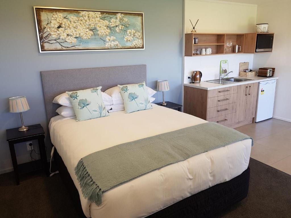 a bedroom with a large bed and a kitchen at Murchison View Studio in Te Anau