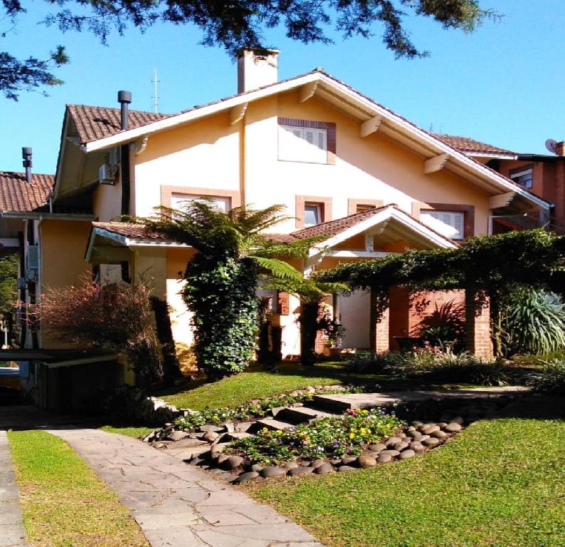 una gran casa blanca con un jardín delante de ella en Apartamento p/ 4 pessoas em Gramado/RS, en Gramado