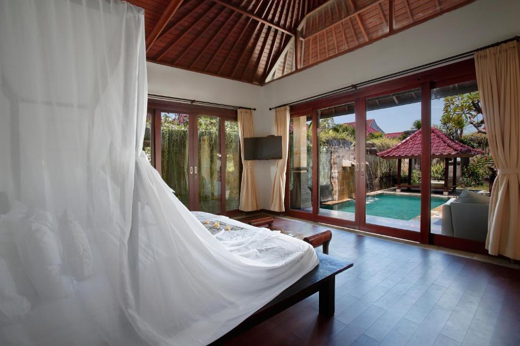 1 dormitorio con cama blanca y piscina en Bali Prime Villas, en Seminyak