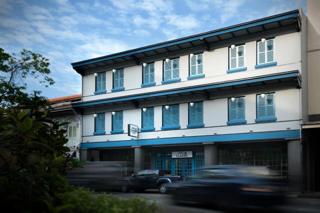 a car driving past a building with blue shutters at Hotel Classic by Venue in Singapore