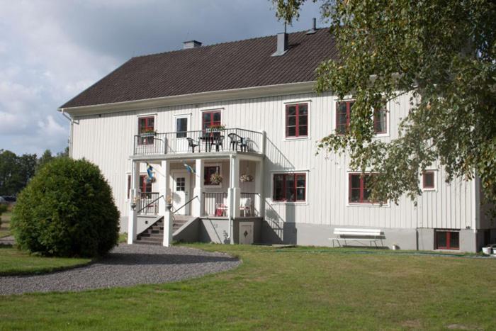 Cette grande maison blanche dispose d'une terrasse couverte et d'un balcon. dans l'établissement Pensionat Klåvasten, à Skövde