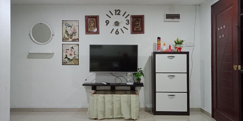 a living room with a television on a white wall at Nadrah Cottage in Bayan Lepas