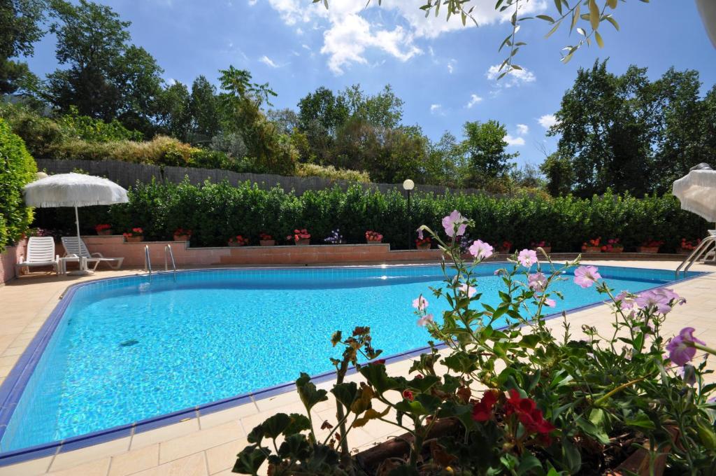 - une piscine dans une cour ornée de fleurs et de plantes dans l'établissement Viole Country Hotel, à Assise