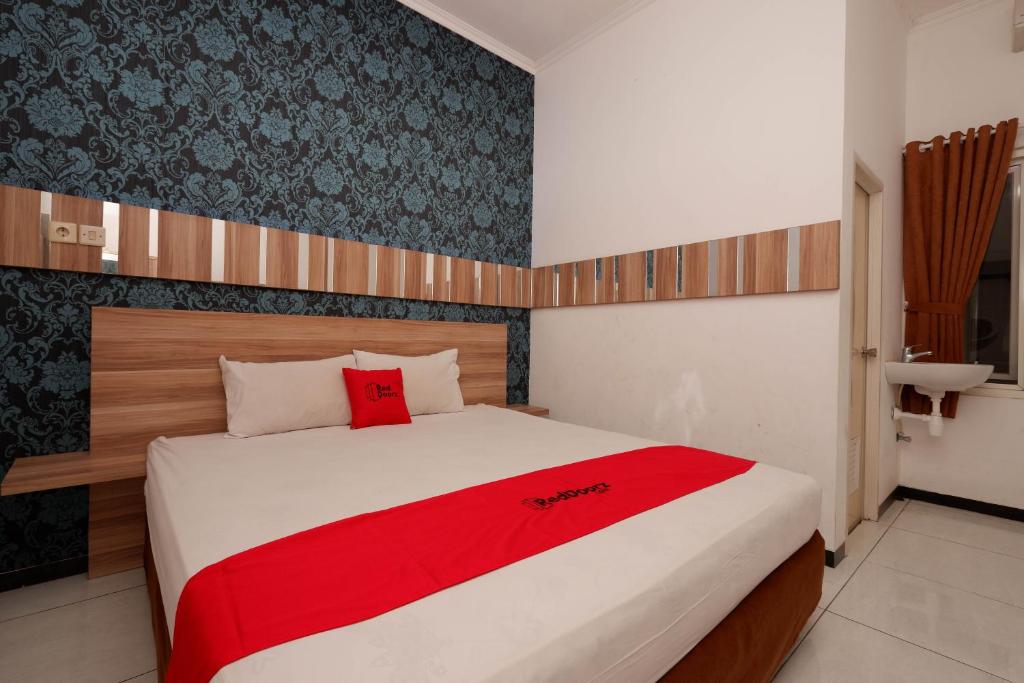 1 dormitorio con 1 cama grande con manta roja en RedDoorz near Plaza Simpang Lima en Semarang