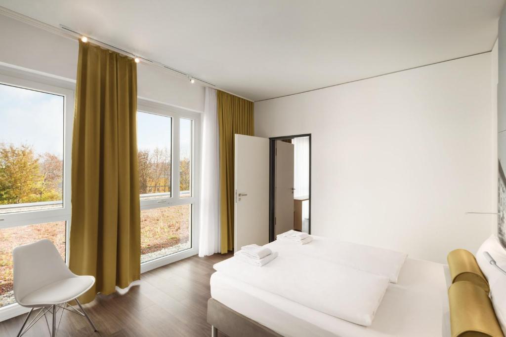 a bedroom with a white bed and large windows at Super 8 by Wyndham Munich City North in Munich