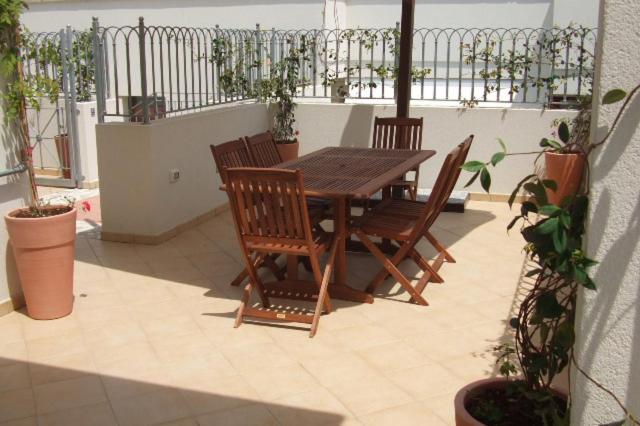 een houten tafel en stoelen op een patio met planten bij Residence La Corte in Porto Cesareo
