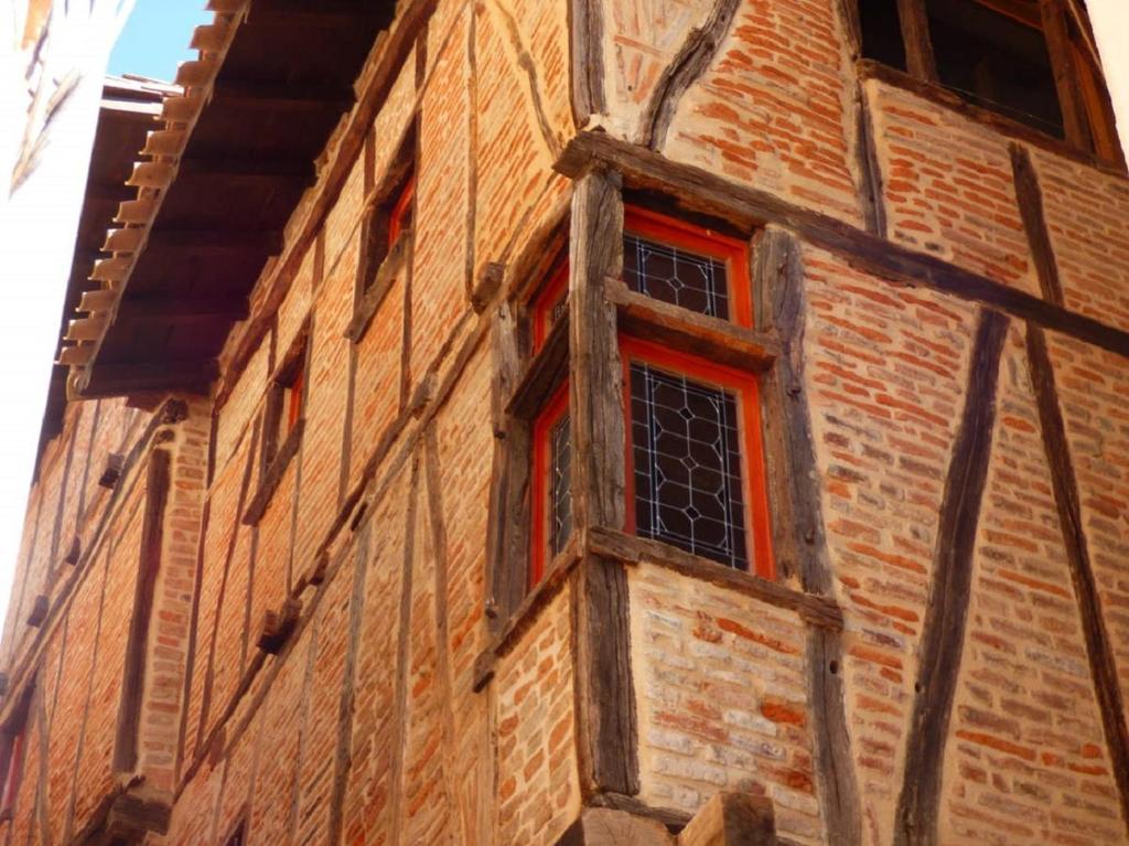 un edificio de ladrillo con ventanas rojas en el lateral. en La lauze et l'anguille, en Gaillac