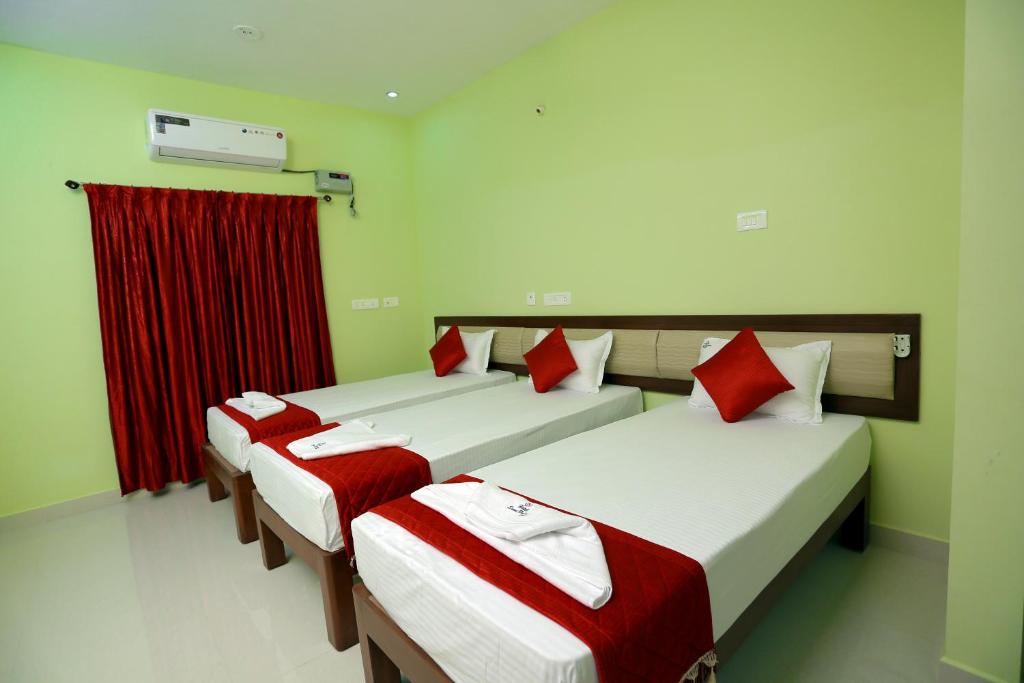 two beds in a room with red curtains at Sumi Palace Annexure in Vallam