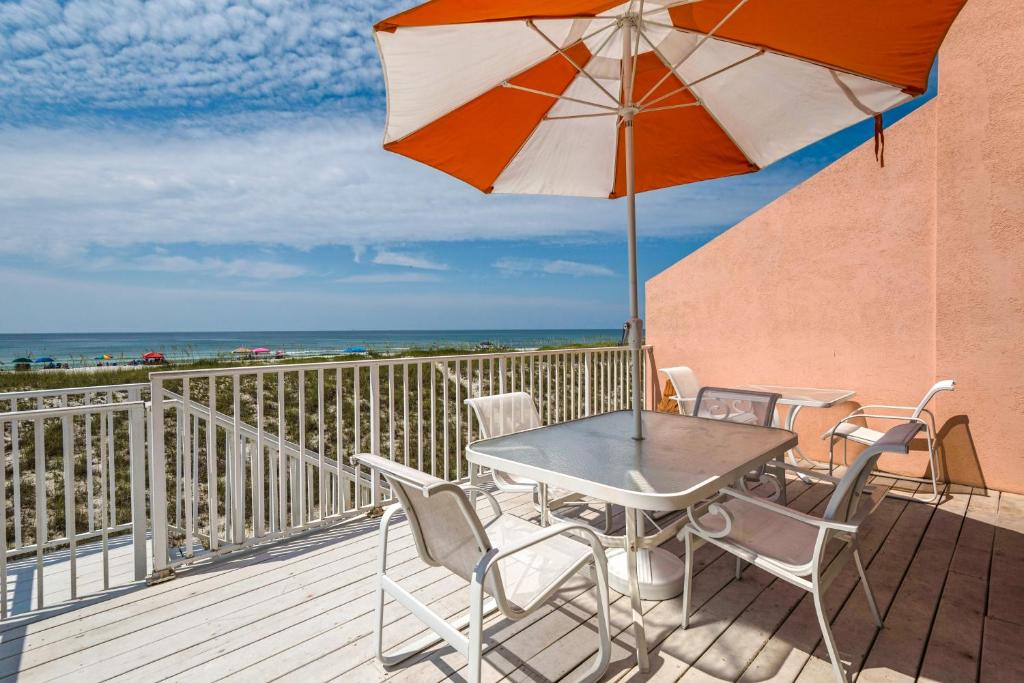 un tavolo e sedie su un balcone con ombrellone di Jen's Creole Cottage a Navarre