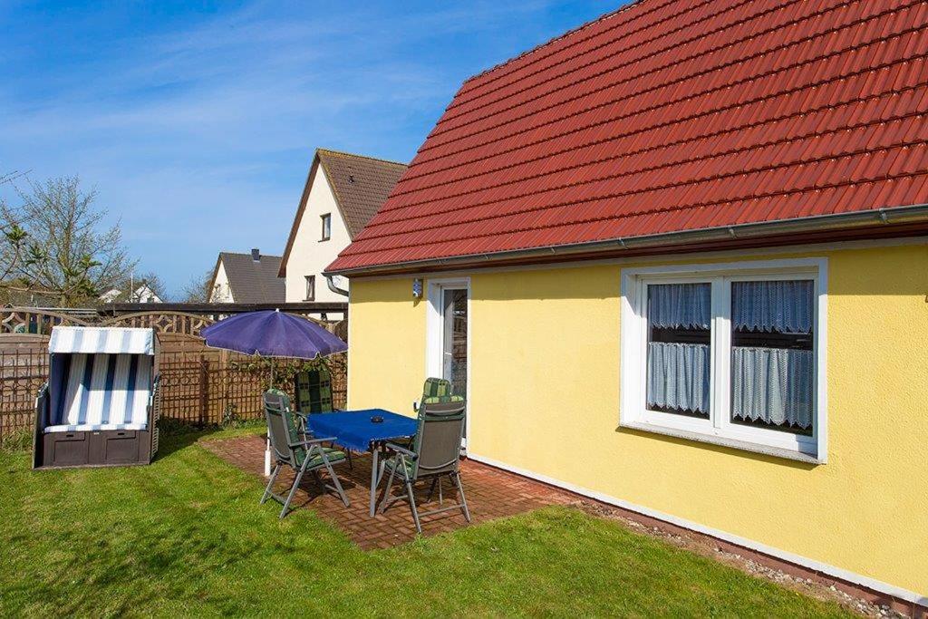 a yellow house with a table and chairs and an umbrella at Zum Lachsfischer in Schaprode