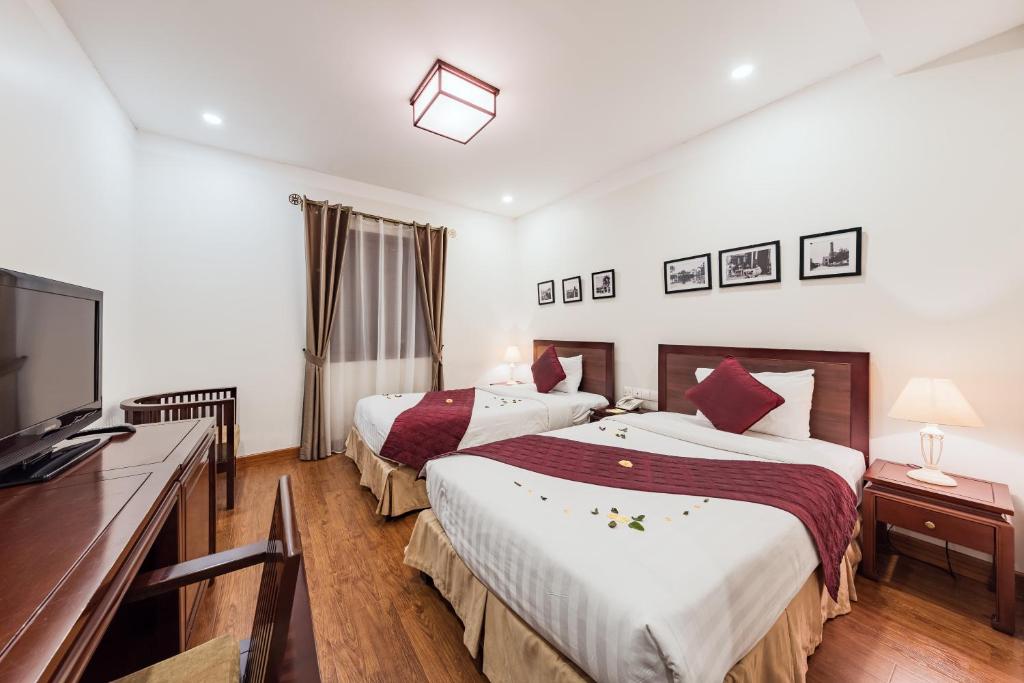 ein Hotelzimmer mit 2 Betten und einem Flachbild-TV in der Unterkunft La Dolce Vita Hotel in Hanoi
