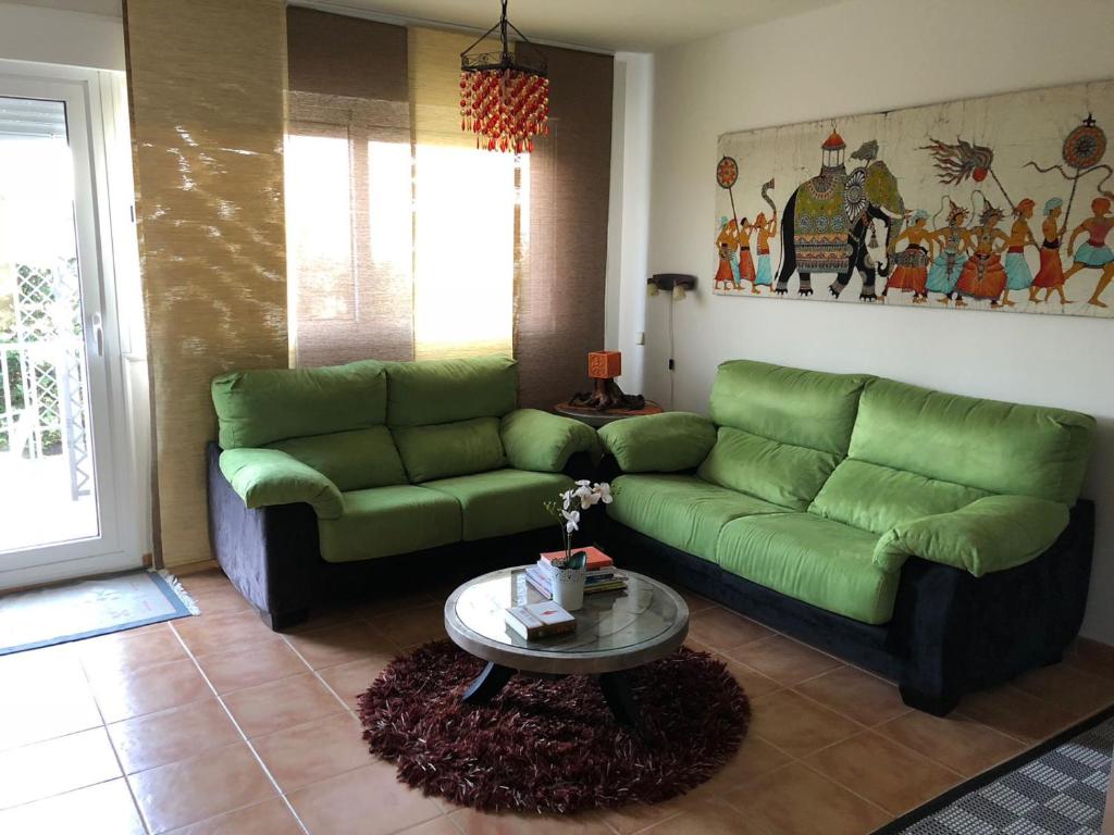 a living room with a green couch and a table at Serengueti in Los Ángeles de San Rafael