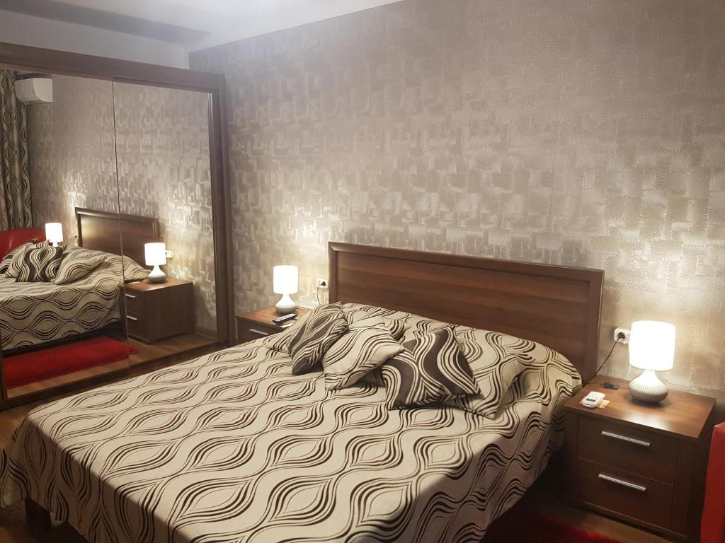 a bedroom with a bed and two tables with lamps at Casa Mirage in Craiova