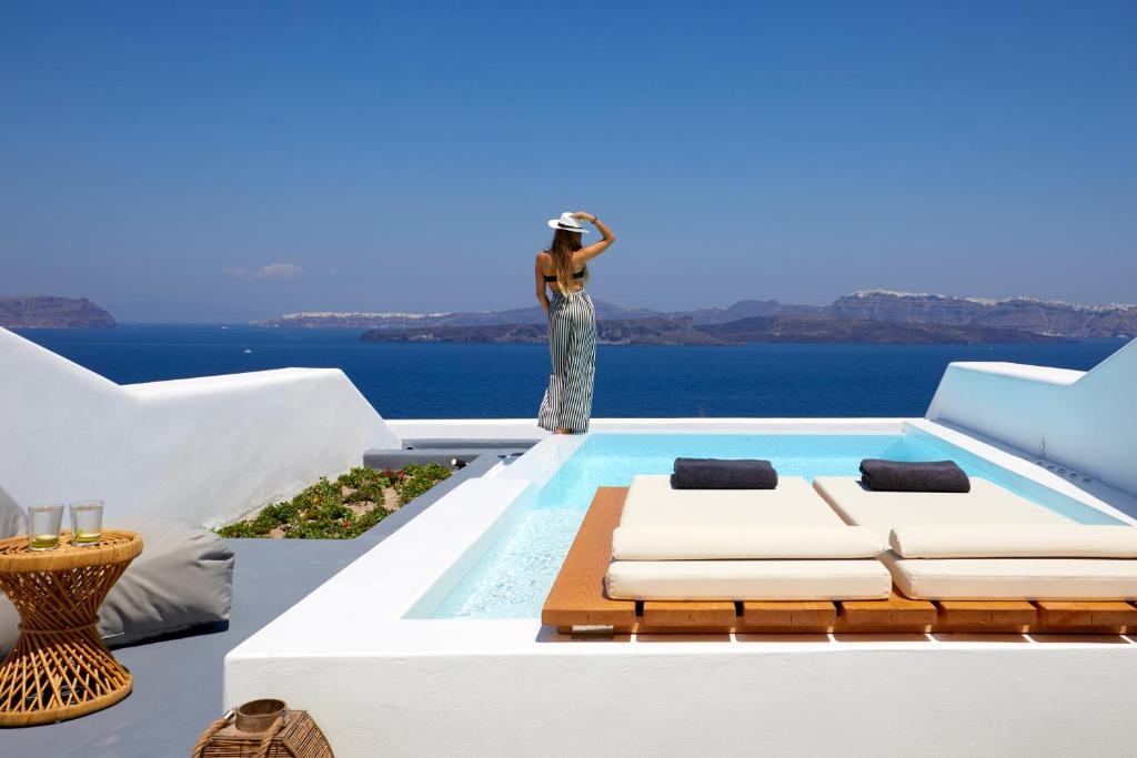 a woman taking a picture of the ocean from a house at Phos The Boutique in Akrotiri