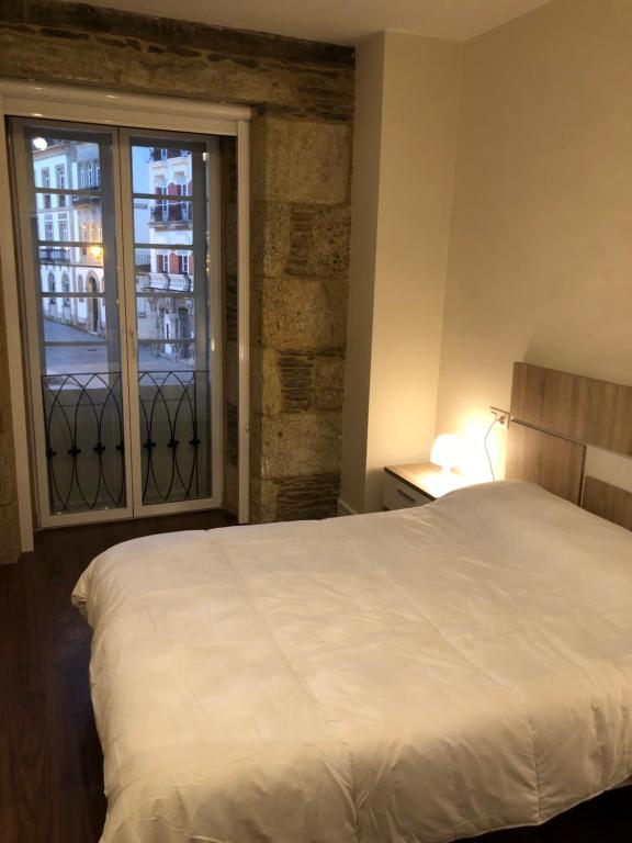 1 dormitorio con cama blanca y ventana en Lugo 360, en Lugo