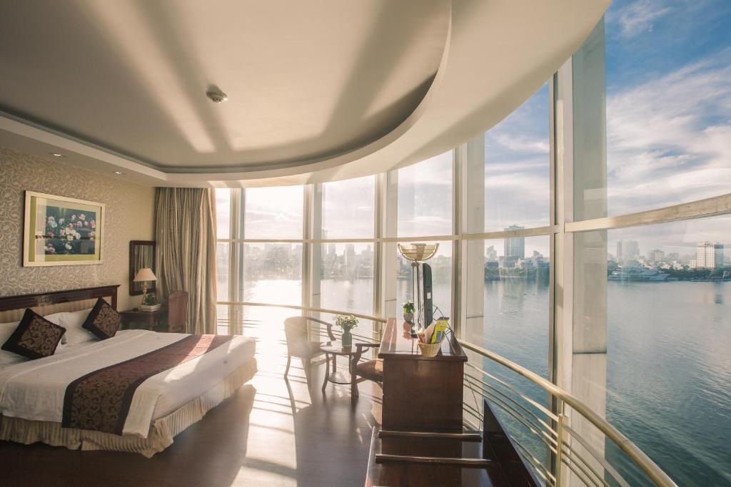 een slaapkamer met een bed en een balkon met uitzicht op het water bij Sun River Hotel in Da Nang