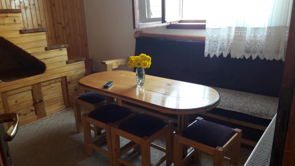 uma mesa com cadeiras e um vaso de flores sobre ela em Apartmani Ćetković em Žabljak